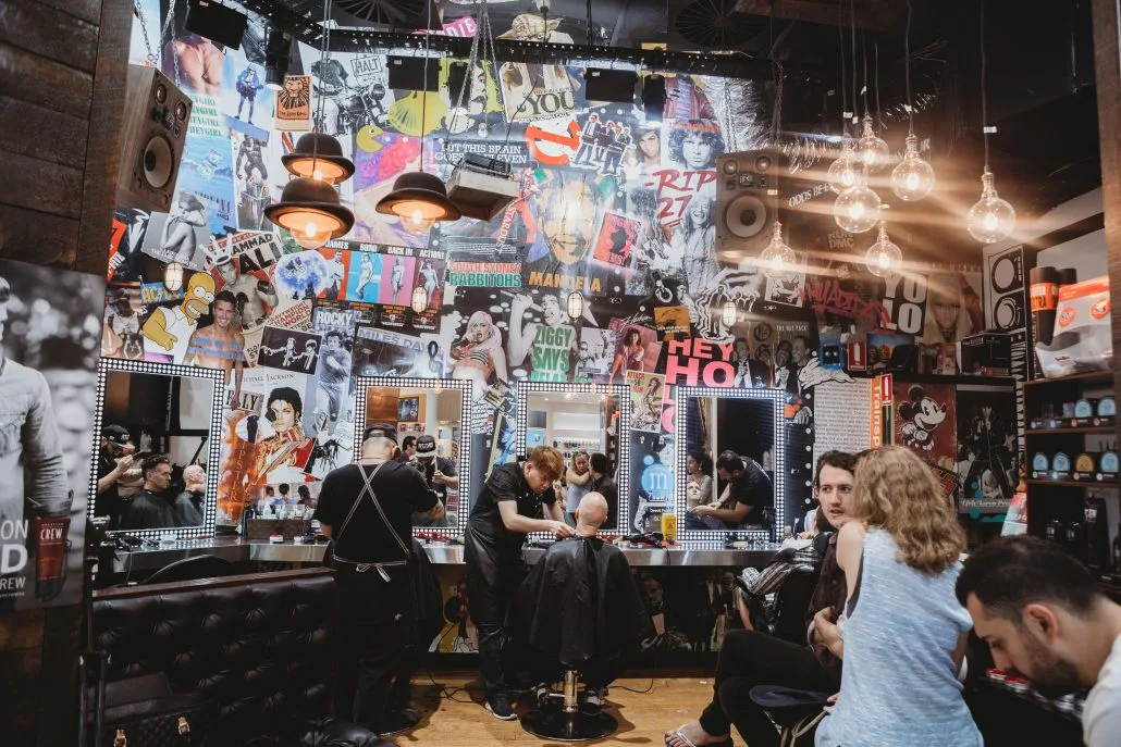 Inside MOE & Co. — the full 90s poster collage wall, caged Edison bulbs, stylists and clients at work