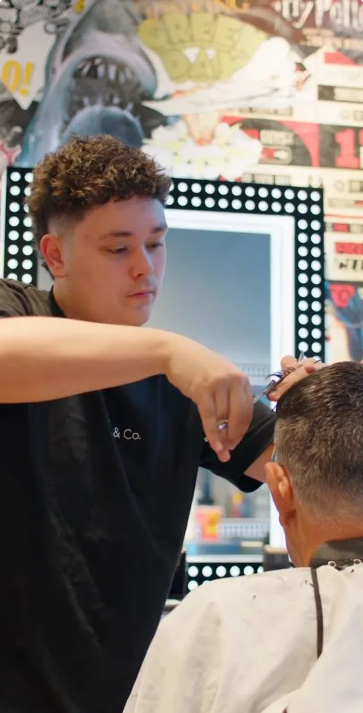 A MOE & Co. stylist at work — scissor-over-comb, focused on the cut